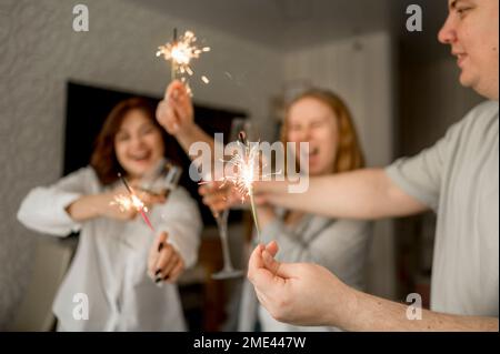 Fröhliche Freunde, die zu Hause Spaß mit Sparklern haben Stockfoto