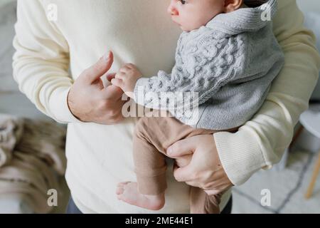 Vater, der zu Hause Händchen hält mit dem kleinen Jungen Stockfoto