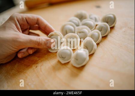 Eine Frau, die Knödel auf dem Schneidebrett arrangiert Stockfoto