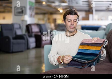 Ein Mann mittleren Alters wählt die Polsterfarbe der Möbel Stockfoto