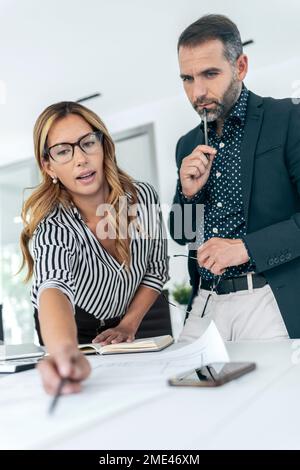 Geschäftsfrau und Geschäftsmann diskutieren Pläne im Amt Stockfoto