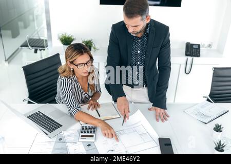 Architekten diskutieren Strategie über Blaupausen am Schreibtisch im Büro Stockfoto