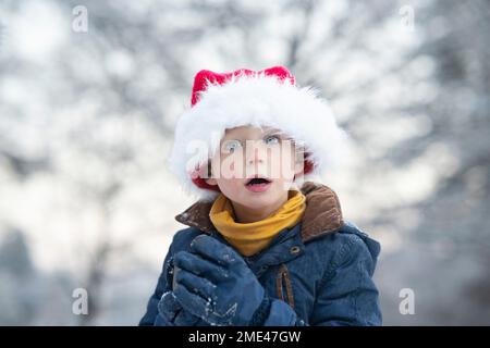 Ein überraschter süßer Junge mit Weihnachtsmannmütze Stockfoto