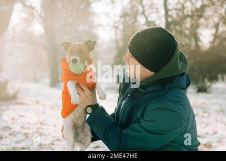 Lächelnder Mann, der im Winter mit einem Hund spielt Stockfoto