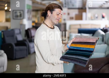 Ein Mann mittleren Alters wählt die Polsterfarbe der Möbel Stockfoto