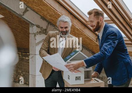 Lächelnde Architekten diskutieren über Baupläne auf der Baustelle Stockfoto