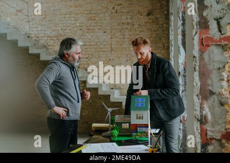 Architekt, der das Modellhaus des Kunden auf der Baustelle erläutert Stockfoto