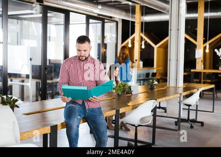 Geschäftsmann, der Dokumente liest, sitzt auf dem Schreibtisch im Büro Stockfoto