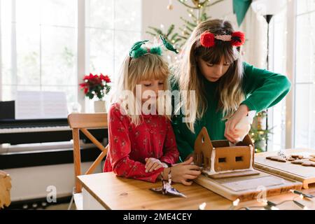 Mädchen, die zu Hause ein Lebkuchenhaus machen Stockfoto