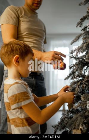 Vater und Sohn schmücken Weihnachtsbaum zu Hause Stockfoto