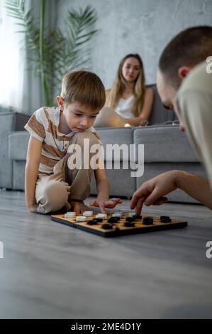 Vater spielt Dame mit Sohn zu Hause Stockfoto