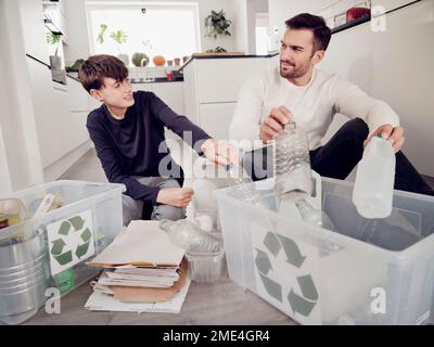 Vater und Sohn trennen Abfälle in Recyclingkisten Stockfoto