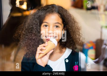 Lächelndes Mädchen, das zu Hause Eis isst Stockfoto