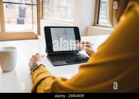 Hand einer Geschäftsfrau, die mit einem digitalen Stift eine Windturbine auf einem Tablet-PC zeichnet Stockfoto