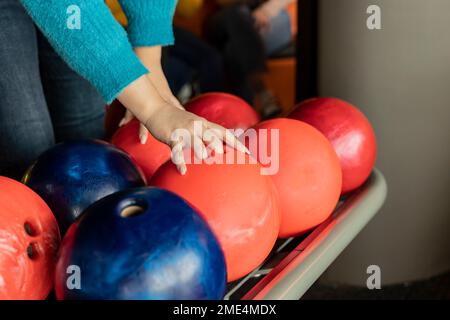 Die Hand einer Frau, die eine Bowlingkugel hebt Stockfoto
