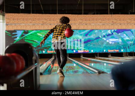 Ein Mann mit kariertem Hemd, der auf der Bowlingbahn spielt Stockfoto