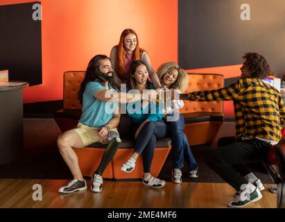 Fröhliche multirassische Gruppe von Freunden, die Biergläser in der Bowlingbahn toasten Stockfoto