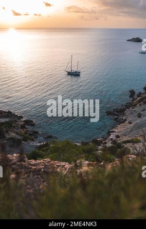 Spanien, Balearen, Segelboot, das bei Sonnenuntergang in der Nähe der Küste schwimmt Stockfoto