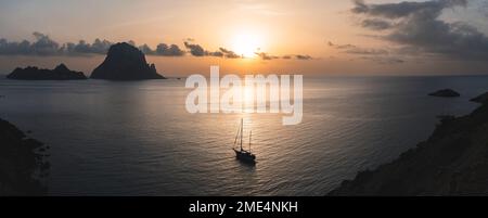 Spanien, Balearen, Segelboot in der Nähe der Küste bei Sonnenuntergang mit Es Vedra im Hintergrund Stockfoto