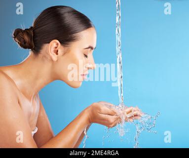 Frau, Hände und Wasser für Hautpflege, Hydratation, Hygiene oder Gesichtswäsche vor blauem Hintergrund. Schöne Frau in der Gesichtsreinigung, beim Waschen oder Stockfoto