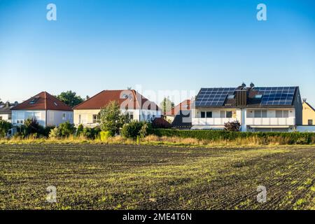 Haus mit Sonnenkollektoren auf dem Dach unter blauem Himmel Stockfoto