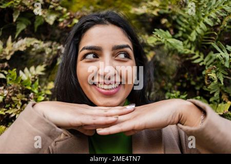 Glückliche junge Frau vor dem vertikalen Garten Stockfoto