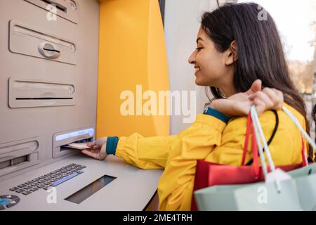 Eine Frau, die Geld vom Geldautomaten abhebt Stockfoto