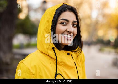 Glückliche junge Frau in einem Regenmantel Stockfoto