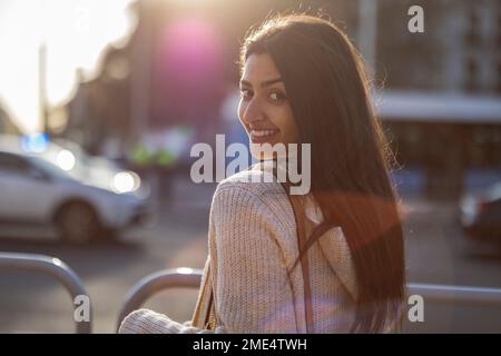 Lächelnde junge Frau, die am Geländer steht Stockfoto