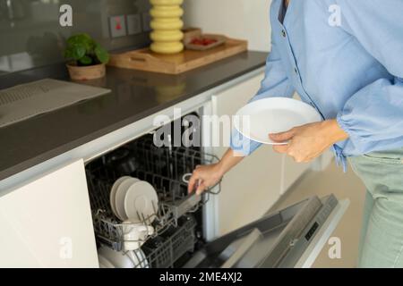 Hände von Frauen, die Teller zu Hause in die Spülmaschine legen Stockfoto