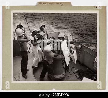 Fünf Steward's Mates an Bord einer von der Küstenwache bemannten Fregatte im Südwesten des Pazifiks bereiten sich auf die Aktion während des Generalquartiers vor. Diese Küstenwächter bemannen eine 20-mm-AA-Kanone, bereit, ihr Schiff zu verteidigen. Von links nach rechts: James L. Wesley (Laden von Granaten), L.S. Haywood (feuern), William Watson (Bericht zur Brücke) und William Morton (Laden eines Clips). Stockfoto