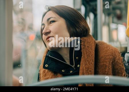 Reife Frau, die in der Straßenbahn durch das Fenster schaut Stockfoto