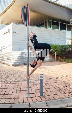 Ein Mann, der vor dem Gebäude Pole Dance praktiziert Stockfoto