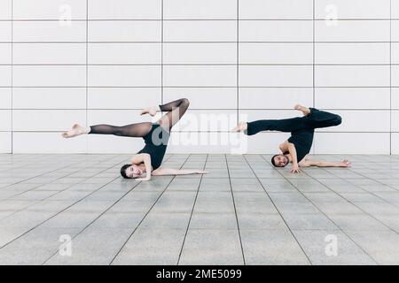 Ein Paar, das einen Kopfständer mit Spalten vor der Wand macht Stockfoto