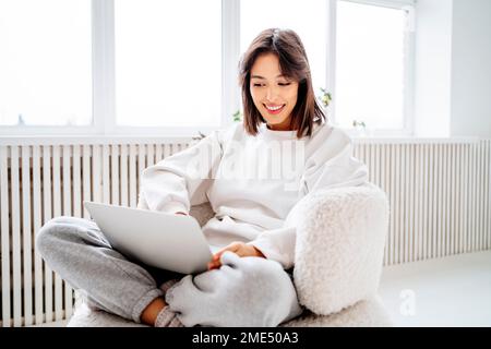 Glückliche junge Frau mit Laptop zu Hause Stockfoto