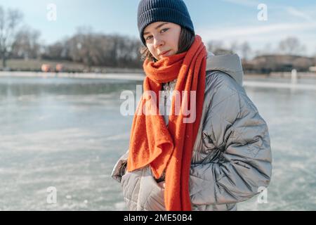 Teenager mit Strickmütze, die auf Eis steht Stockfoto