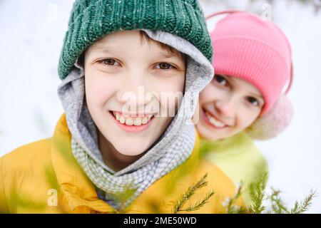 Glückliche Geschwister, die Strickmützen im Schnee tragen Stockfoto