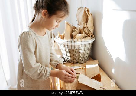 Süßes Mädchen, das zu Hause Geschenke am Schrank öffnet Stockfoto