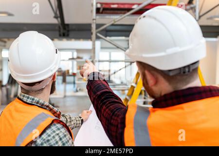 Junge Ingenieure tragen Schutzhelme, die sich vor Ort untersuchen und besprechen Stockfoto