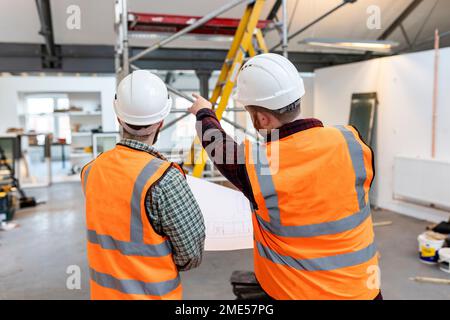 Techniker tragen Schutzhelme, die vor Ort prüfen und diskutieren Stockfoto