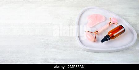 Rose Quartz Roller und Gua Sha Tool, Gesichtslifter-Kratzer-Massagebehandlung Stockfoto