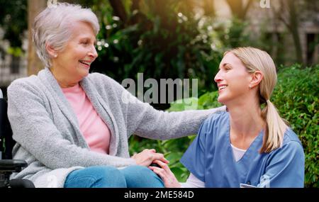 Vielen Dank für Ihre Hilfe. Eine fröhliche ältere Frau im Rollstuhl, die Zeit mit ihrer Tochter draußen im Park verbringt. Stockfoto