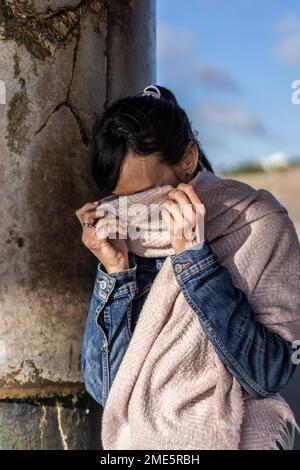 Porträt einer schüchternen Frau, die ihr Gesicht mit einem Schal bedeckt Stockfoto