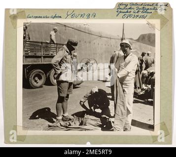 Long Island Coast Guard Invader Interpreter für Yanks in Oran. Der Küstenwächter Alfred Young, Yeoman, dritte Klasse, Besatzungsmitglied eines robusten, von der Küstenwache bemannten Invasionstransports, agiert als Mitglied einer Suchtruppe in Oran, Nordafrika, und gibt den Nazi-Supermännern einen gründlichen Yankee, der sie überfährt. Coast Guardsman Young, geboren in Nürnberg, Deutschland und aufgewachsen in den Vereinigten Staaten, spricht fließend die deutsche Sprache und wird dabei unterstützt, als Dolmetscher zwischen den deutschen Gefangenen und unseren Streitkräften zu fungieren. Ein Veteran der Invasion von Sizilien und seit der Zeit dieses Fotos, von drei Invasionen im Pazifiktheater Stockfoto