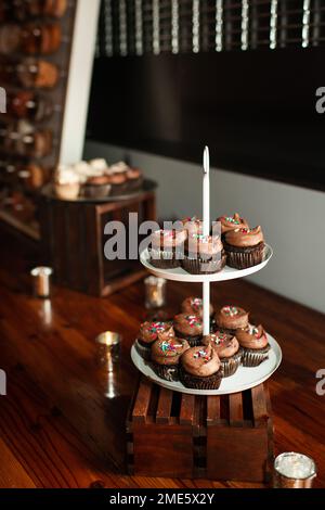 Schokoladentörtchen mit Streuseln auf dem Tablett auf dem Holztisch Stockfoto