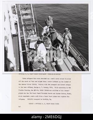 Foto von kubanischen Flüchtlingen - USCGC Ingham in Florida Straits. Kubanische Flüchtlinge, die auf einer kleinen Koralleninsel 14 Meilen vor der Küste Kubas gestrandet waren, erhalten Hilfe von einem Motorrettungsboot auf der Leiter der Rettungsstation Cutter Ingham. Mit dem jüngsten und barsten Flüchtling zu helfen, ist der Bootsoffizier, Fähnrich A.T. Pferdchen, USCG. Während des Betriebs in der Straße von Florida wurde das 327 m hohe USCGC Ingham über das 7. Coast Guard District Search and Rescue Center, Miami, über die Notlage der Kubaner informiert, das einen Funkruf von einem Flugzeug der Küstenwache erhielt, das die Flüchtlinge gesichtet hatte. Inghams Homeport ist Nor Stockfoto