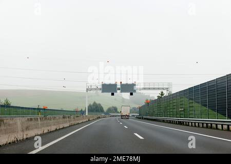 Autobahn im ländlichen Europa mit einsamem Anhänger, der schnell auf der mehrspurigen Autobahn fährt – Rückansicht Stockfoto