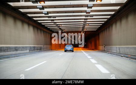 Österreich - 30. Sept. 2014: Rückansicht des blauen Fiat Car Enterngin Austrian Tunnel - gelbe Lichter und immense Perspektive Stockfoto