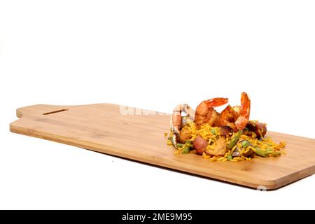 Paella-Reis auf einem Holzbrett mit Salzstreuer und Gabeln, zubereitet mit Meeresfrüchten, Amaronen, Safran, Wurst, Fleisch. Traditionelles Gericht von Valenci Stockfoto