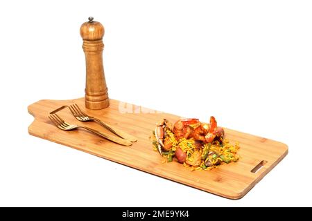 Paella-Reis auf einem Holzbrett mit Salzstreuer und Gabeln, zubereitet mit Meeresfrüchten, Amaronen, Safran, Wurst, Fleisch. Traditionelles Gericht von Valenci Stockfoto